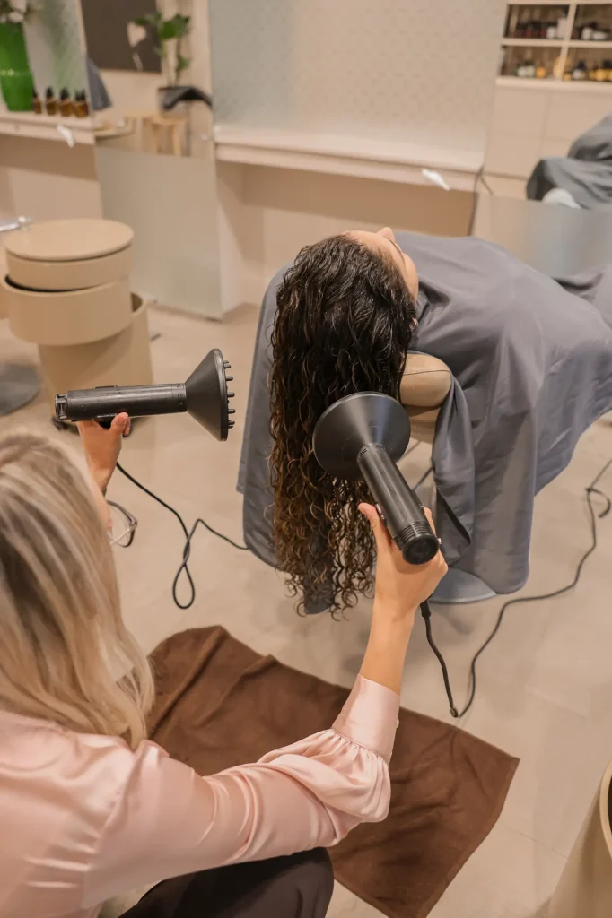 Krullend haar wordt gestyled met een fohn bij Nature Hair Experience