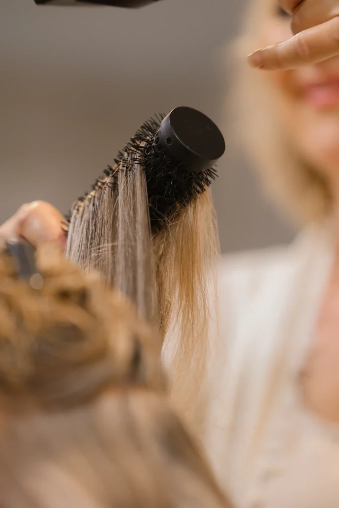 Blond haar wordt gestyled met een ronde borstel bij Nature Hair Experience