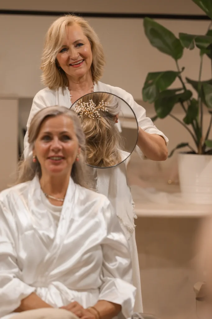 Stylist bevestigt een sierlijke haaraccessoire bij een klant in de salon